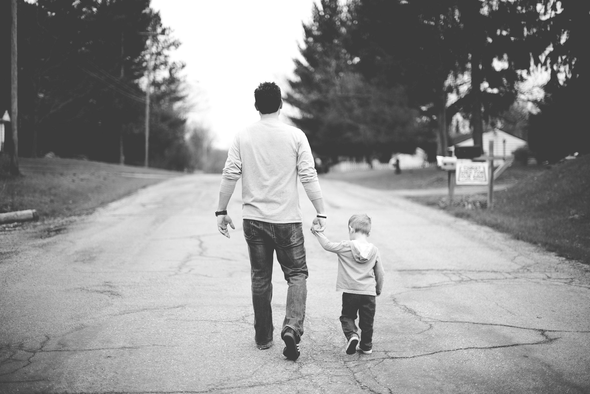 Vater und Sohn gehen Hand in Hand eine Straße entlang