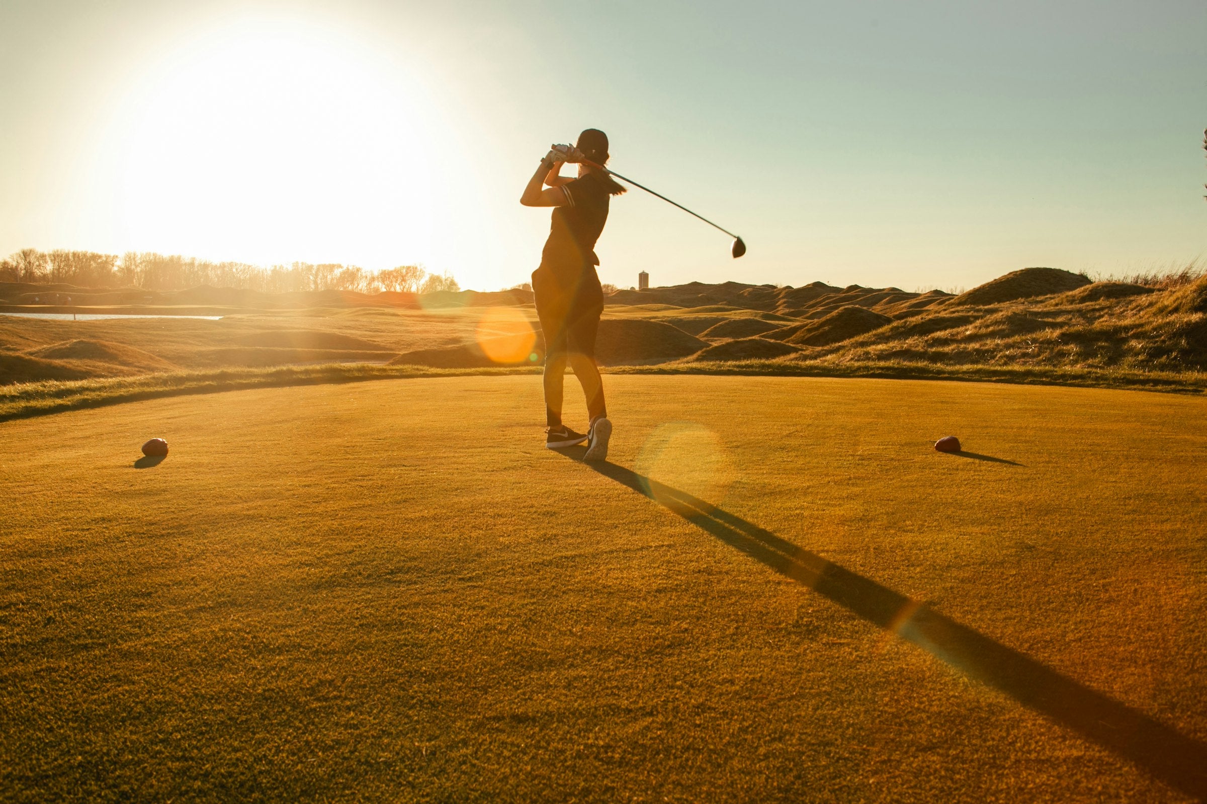 Golfer im Rückschwung bei Sonnenaufgang auf dem Abschlag