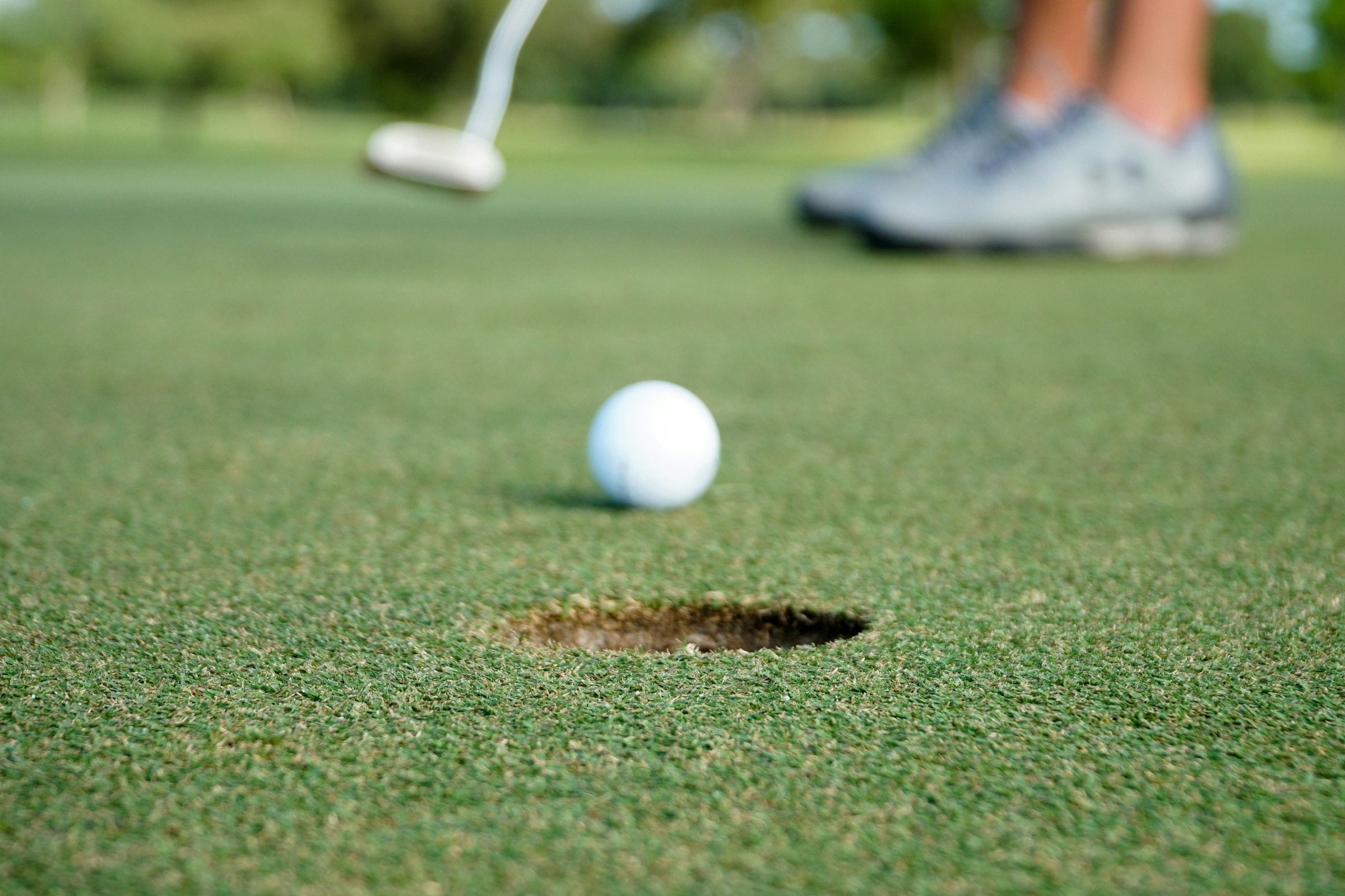 Golfball rollt auf dem Grün Richtung Loch