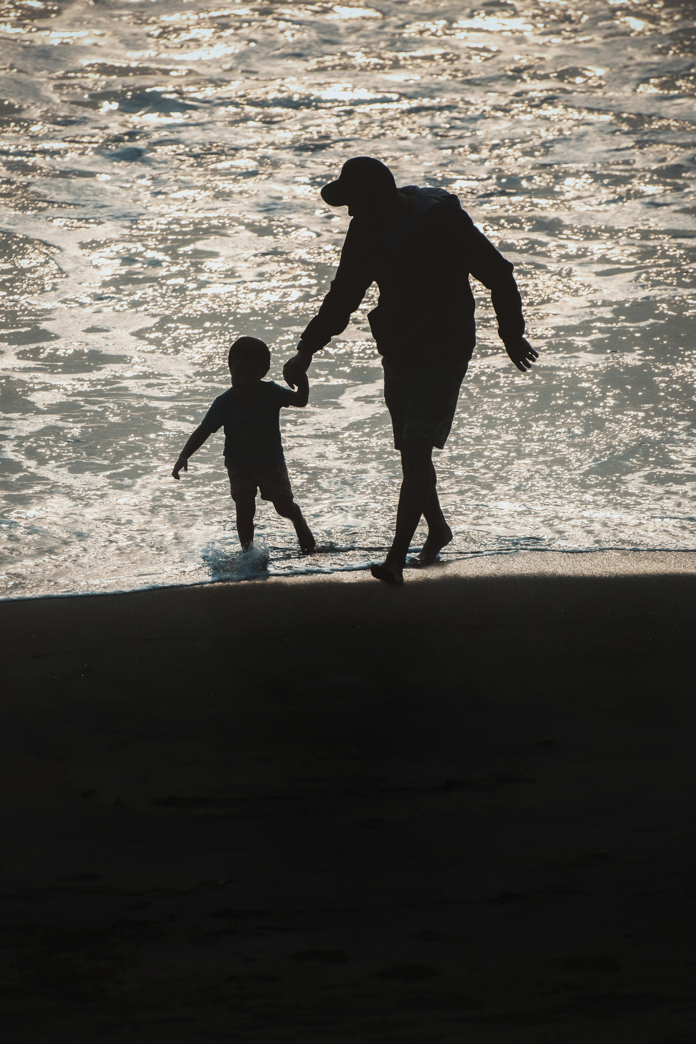 Erwachsener und Kind spazieren am Strand