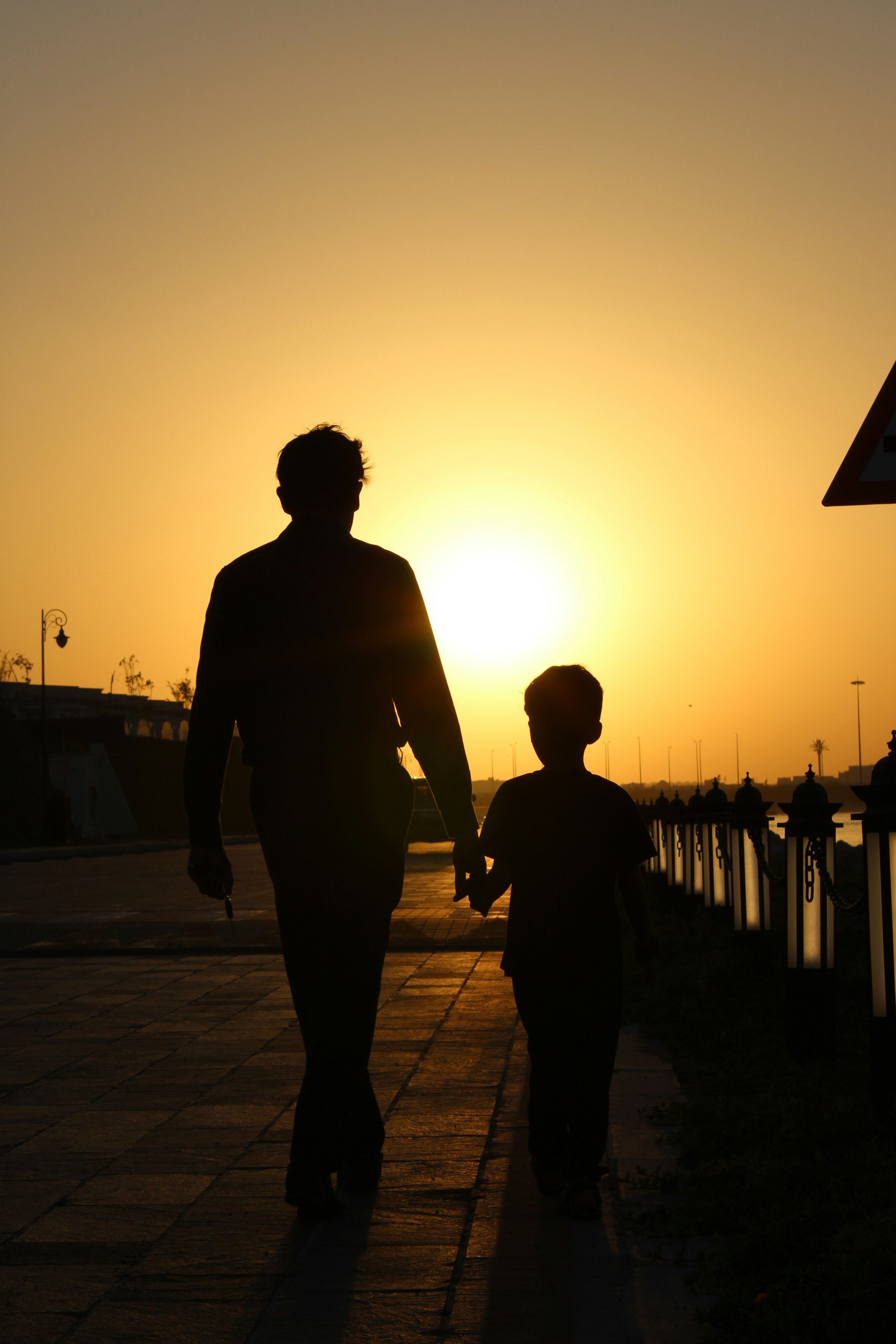 Vater und Kind gehen Hand in Hand im Abendlicht
